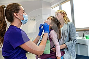 Female dentist examining teeth of little girl at dental clinic