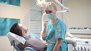 Female dentist examining teeth of male patient. Slider shot, left.