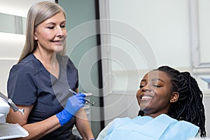 Female dentist examining woman patient with tools in dental clinic getting dental treatment