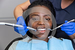 Female dentist examining woman patient with tools in dental clinic getting dental treatment