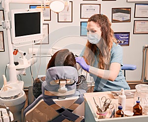 Female dentist examining woman teeth in dental office.