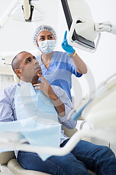 Female dentist explaining teeth radiography result to patient