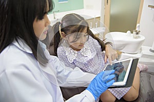 Female dentist explaining teeth x-ray to a little girl in dental clinic, teeth check-up and Healthy teeth concept
