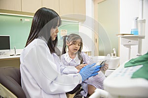 Female dentist explaining teeth x-ray to a little girl in dental clinic, teeth check-up and Healthy teeth concept