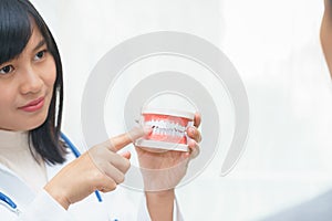 Female dentist fingers pointing at teeth model with patient.