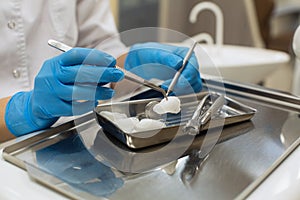 Female dentist hands holding dental tools over medical office background.