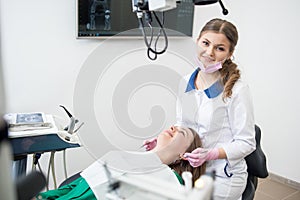 Female dentist with happy patient during dental procedure in the dental clinic. Dentistry. Stomatology equipment