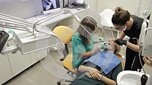 A female dentist and her assistant working on a patients teeth