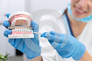 Female dentist holding professional stomatology tool and pointing at the teeth model. Dental hygiene and health concept