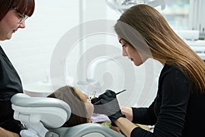 Female dentist hygienist using dental mirror and probe, checking child teeth during regular check-up in dentistry clinic