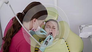 Female dentist making professional brushing child's teeth with a dental tools