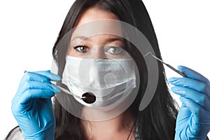 Female dentist in mask holding tool and mirror