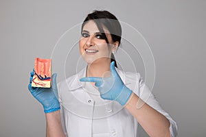 Female dentist with model gingiva isolated over the grey background.