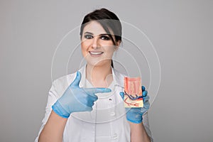 Female dentist with model gingiva isolated over the grey background.