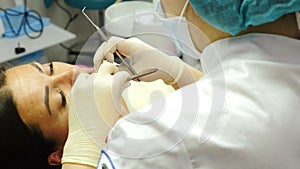 Female dentist orthodontist examines patient teeth at dental chair, dental procedure in clinic. , close-up