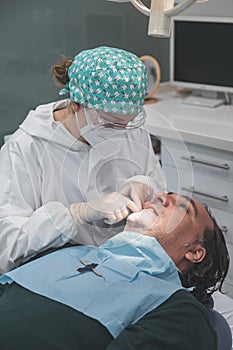 Female dentist with a patient in her office. Patient with open mouth and woman dentist working. dental health concept