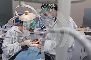 Female dentist with a patient in her office. Patient with open mouth and woman dentist working. dental health concept