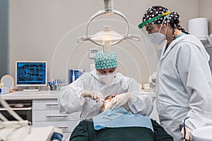 Female dentist with a patient in her office. Patient with open mouth and woman dentist working. dental health concept