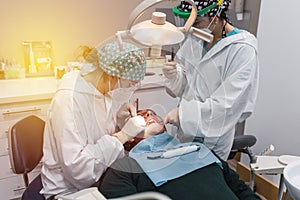 Female dentist with a patient in her office. Patient with open mouth and woman dentist working. dental health concept