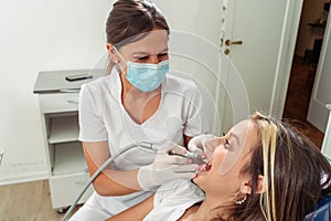 Female dentist performing a lathe treatment on an adolescent patient. Concept dental care, health care