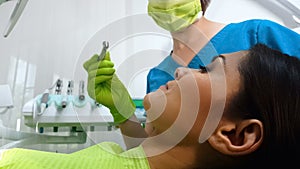 Female dentist preparing to drill patients lower bicuspid teeth, dental services photo