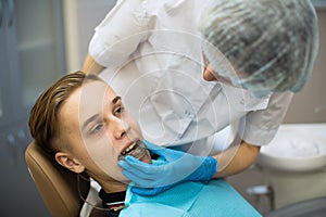 Female dentist puts on a guy patient a mouth guard in dental clinic.