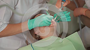 Female dentist removing braces patient teeth at dental clinic office. Medicine, dentistry concept. Dental equipment