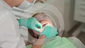 Female dentist removing braces patient teeth at dental clinic office. Medicine, dentistry concept. Dental equipment