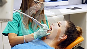 A female dentist repairing a young woman`s teeth, the patient turns and smiles into camera