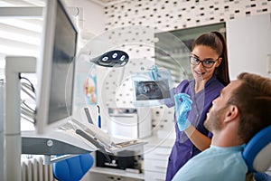 Female dentist showing dental x-ray footage to patient photo