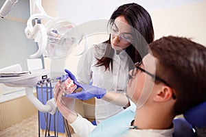 Female dentist showing teeth model to the patient