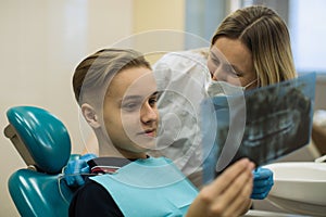 Female dentist showing to patient x-ray the jaw at medical clinic.