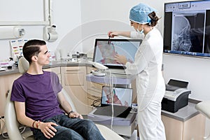 Female dentist showing tooth cavity to patient