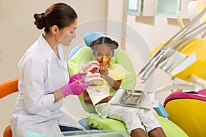Female dentist showing toothbrushing technique to her patient