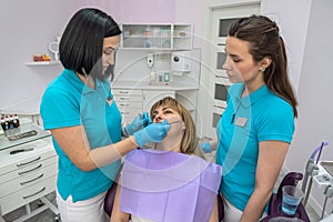 female dentist shows a girl trainee how to properly examine the oral cavity.