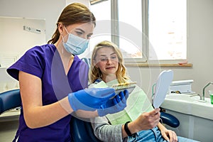 female dentist in special clothes selects natural color of teeth for whitening a patient.