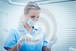 Female dentist in surgical mask holding dental tools