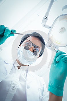 Female dentist in surgical mask holding dental tools