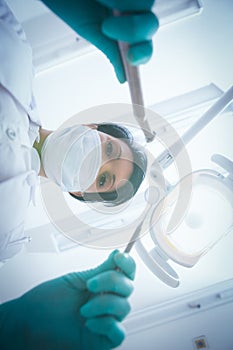 Female dentist in surgical mask holding dental tools