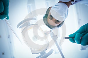 Female dentist in surgical mask holding dental tools