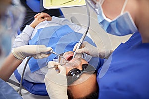 Female dentist treating male patient teeth