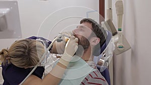 Female dentist is treating a patient in dental clinic. Dental check up. Stomatologist treats caries in patient`s teeth