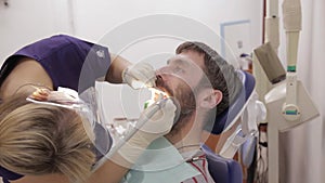 Female dentist is treating a patient in dental clinic. Dental check up. Stomatologist treats caries in patient`s teeth