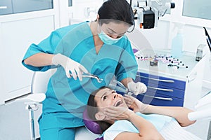 A female dentist is treating a patient. She sits on the dental chair and is afraid.