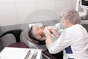 A female dentist treats the teeth of a male patient in the office of a dental clinic.Concept of medicine, dentistry and