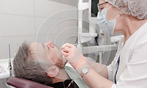 A female dentist treats the teeth of a male patient in the office of a dental clinic.Concept of medicine, dentistry and