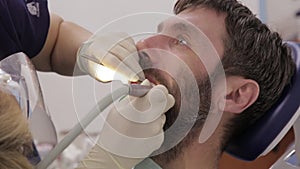 Female dentist treats teeth to male patient. Stomatologist treats caries in patient`s teeth. Dental oral hygiene