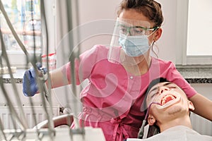 A female dentist treats tooth decay on a male patient`s teeth at a dental clinic