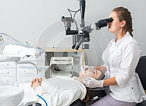 Female dentist using dental microscope treating patient teeth at dental clinic office. Medicine, dentistry and health