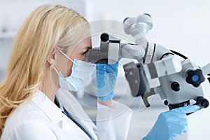 Female dentist using modern equipment for treating in dental clinic